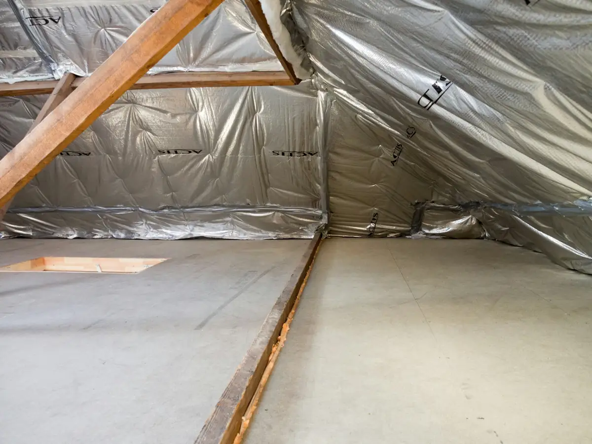 Combles sous toiture doublés d'un isolant réfléchissant, fermettes en bois et plancher