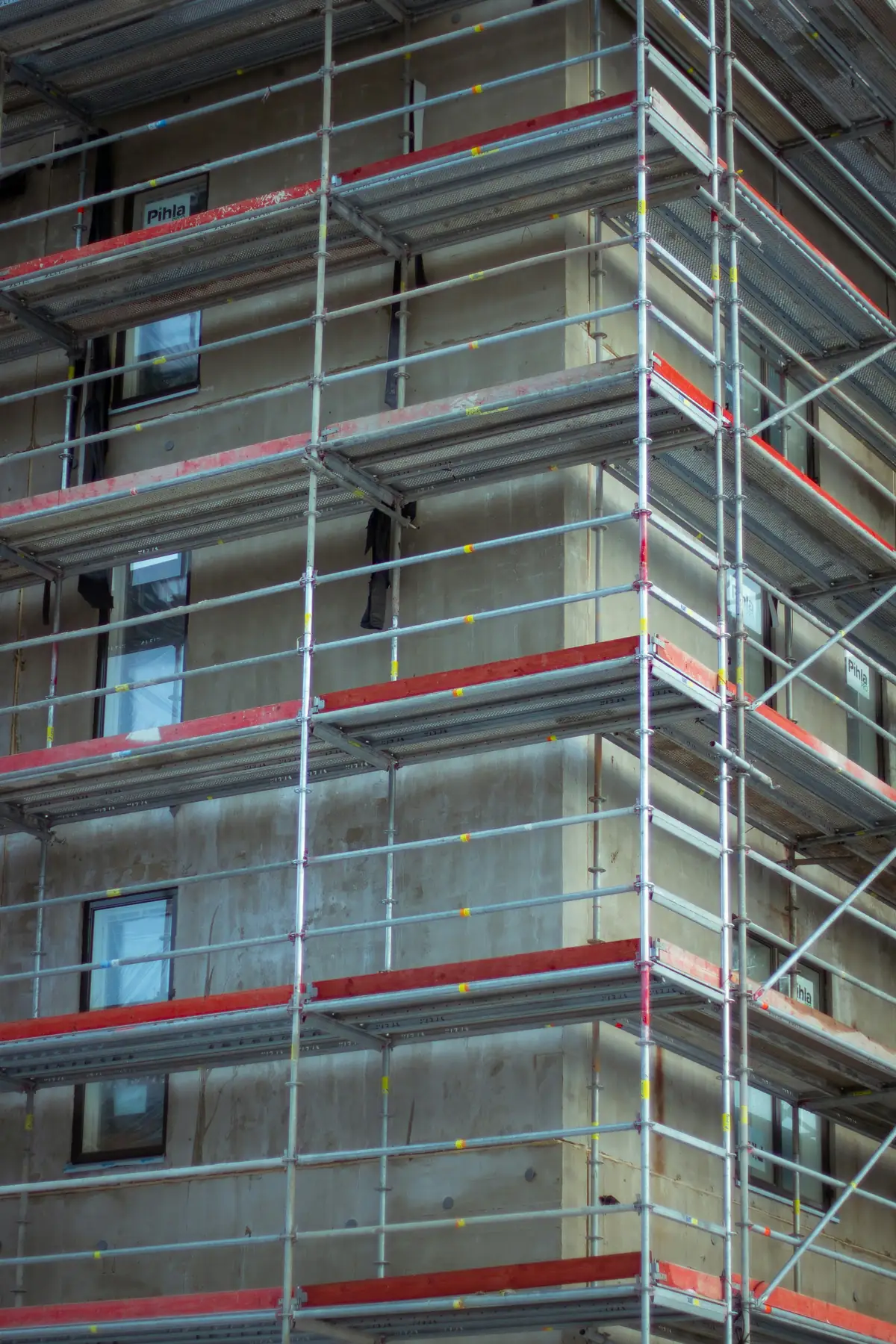 Immeuble en béton entièrement monté d'échafaudages, filets et garde-corps rouges