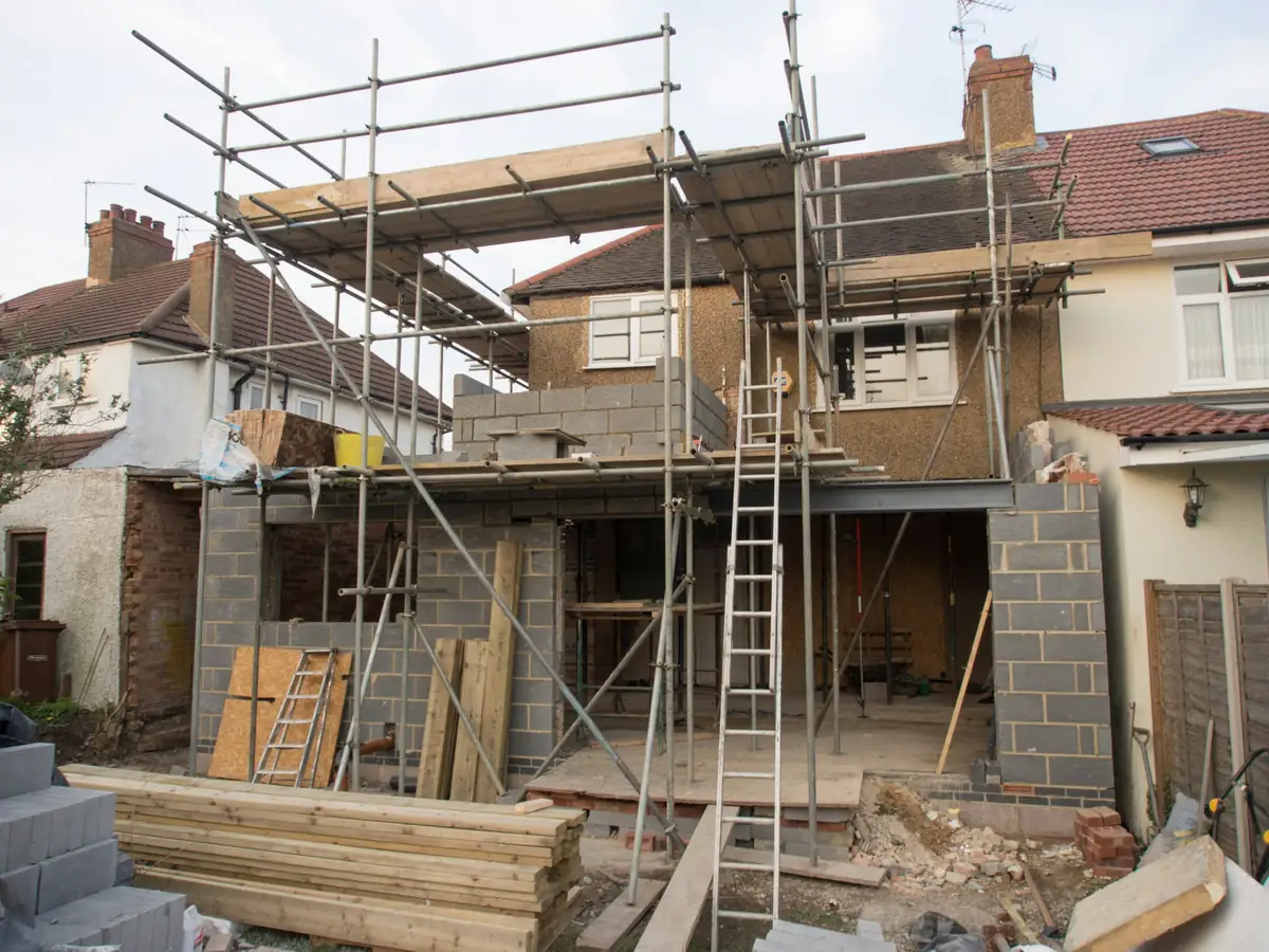 Agrandissement en cours à l'arrière d'une maison : murs en blocs, échafaudage et échelle