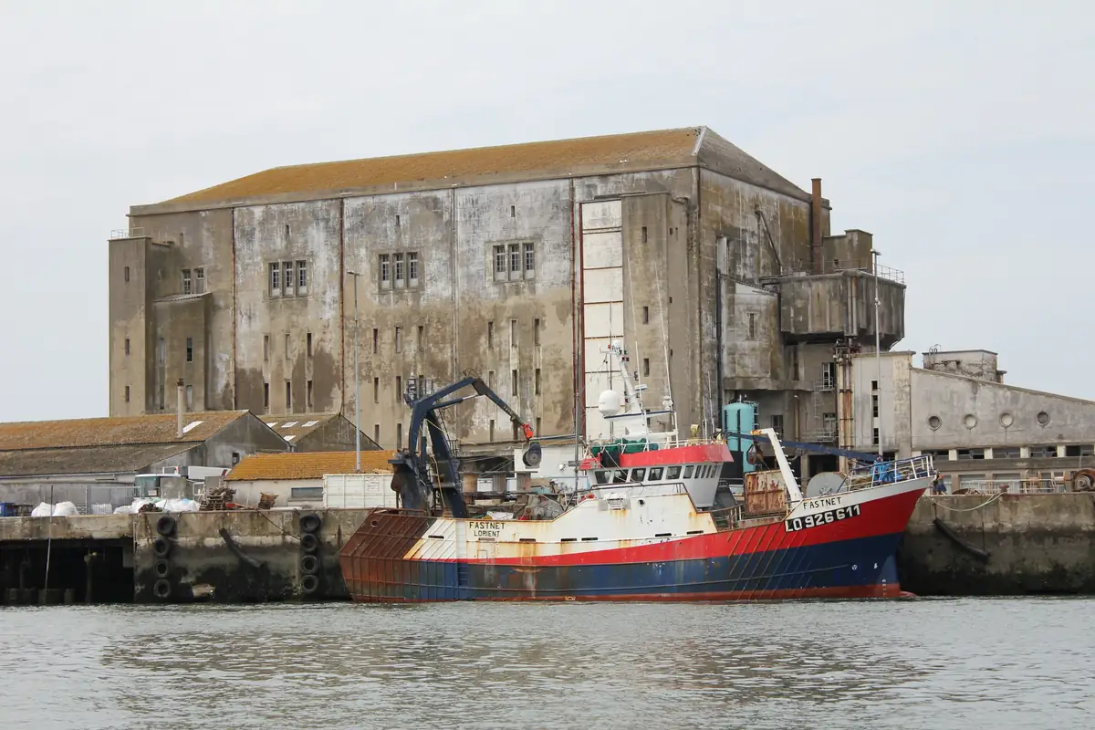 Chalutier à quai devant la glacière en béton du port de pêche de Keroman