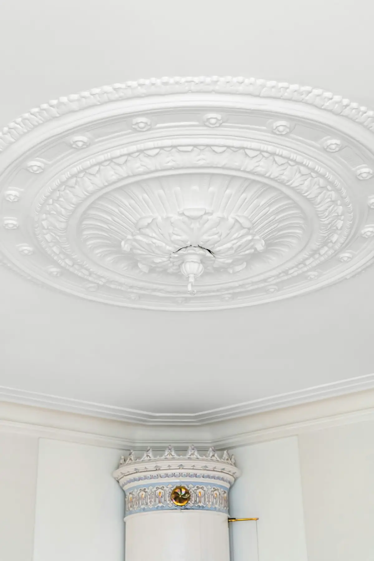 Rosace et corniche moulurées en plâtre blanc au plafond d'une pièce ancienne