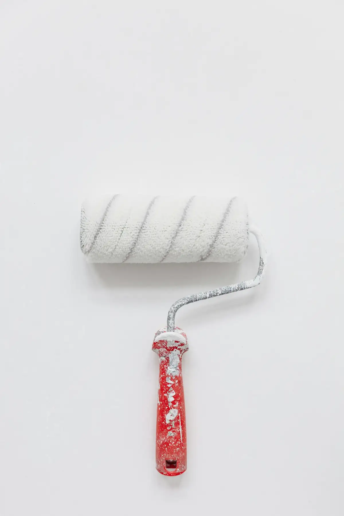 Rouleau de peinture blanc posé contre un mur blanc