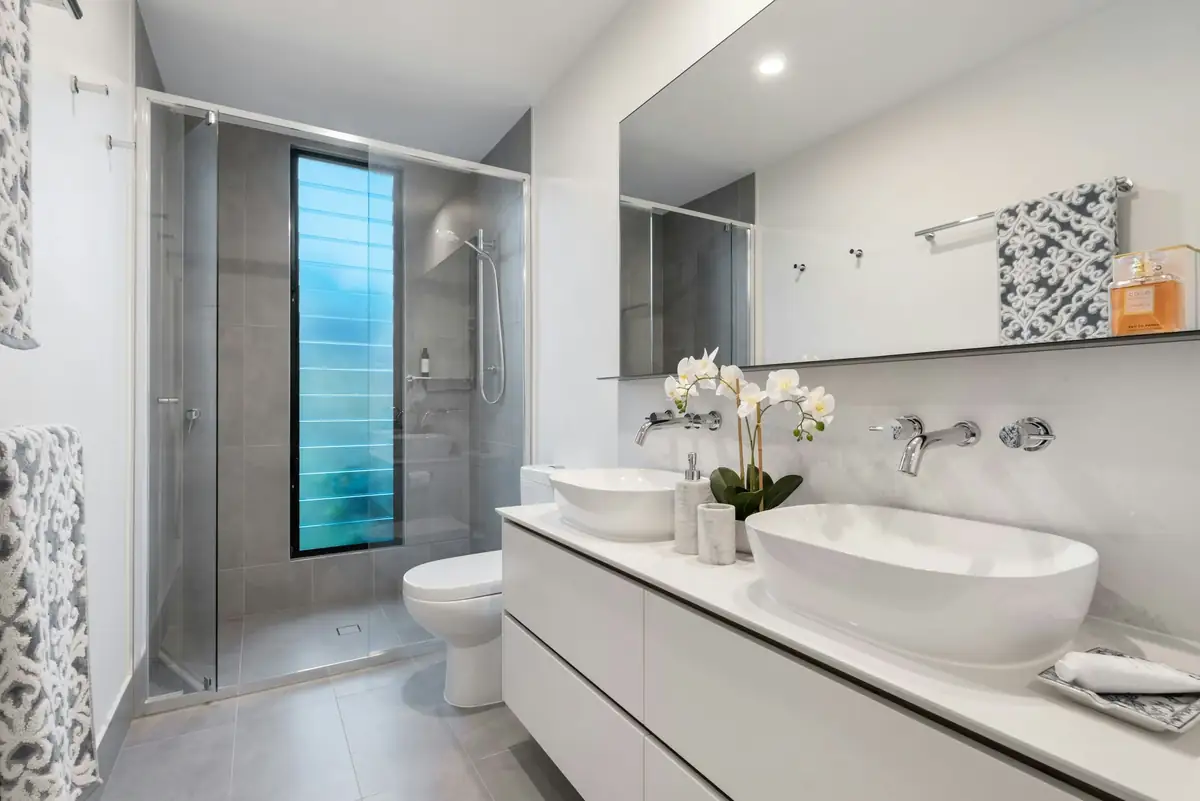 Salle de bain carrelée de gris, double vasque et douche à l'italienne